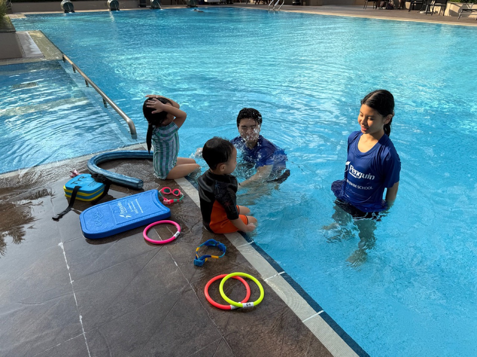Penguin Swim School female coach supporting children during swimming lesson preparation in Singapore