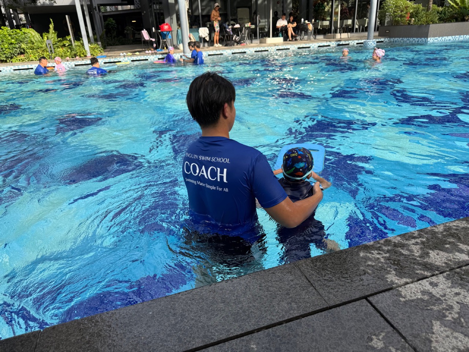 Penguin Swim School coach supervising a child in a visible Singapore pool setting